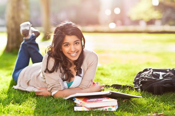 student laying on grass studying