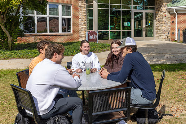 Friends on campus Students visiting at picnic table outside Port Sky Cafe