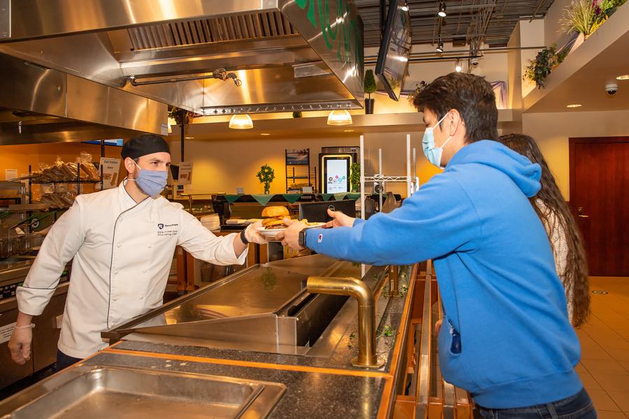 Student receiving food item from employee