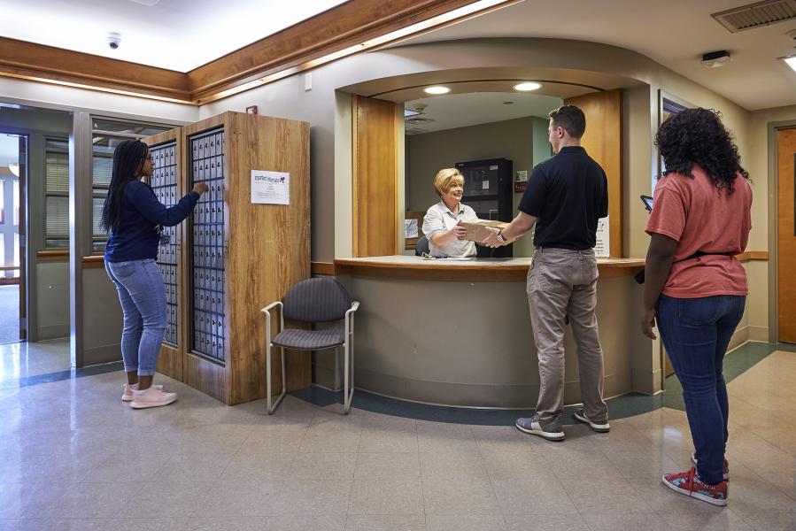 Staff giving student package at mailroom in Bowman Hall