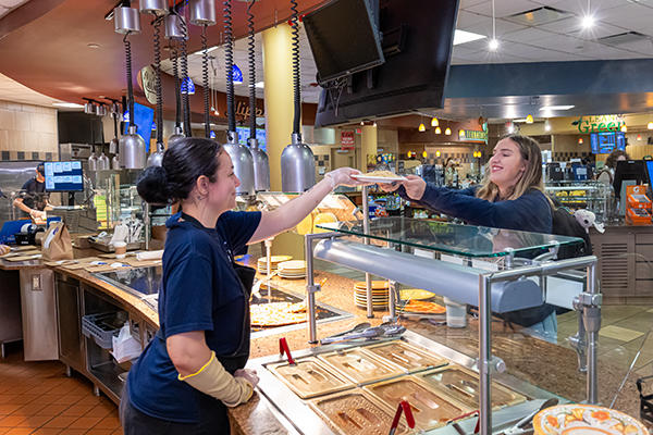 Dining employee hands food to student 