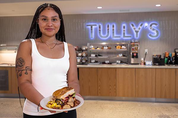 Student holds their lunch in front of the Tully's sign