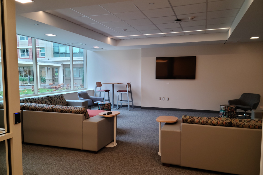 Hastings common area lounge with chairs and small tables with TV on wall