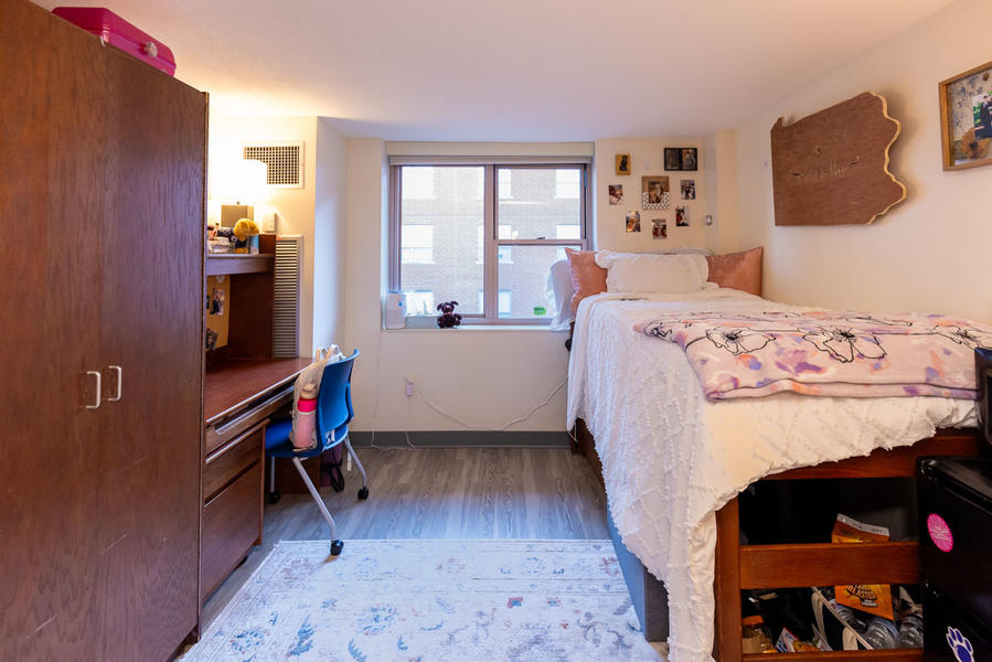 Dorm bedroom with bed to the right and wardrobe to the left, camera is facing the window straight ahead