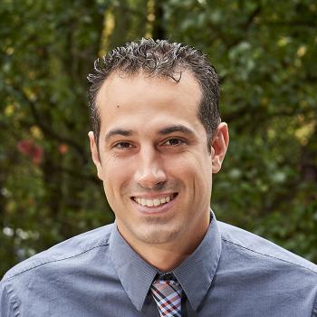 A smiling Mark Tranguch in front of a woodsy background