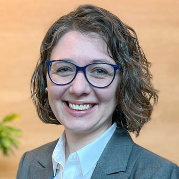 A smiling Elizabeth Kearns in front of a pale wood backdrop