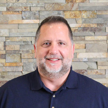 A smiling Claudio Tarallo in front of a natural stone backdrop