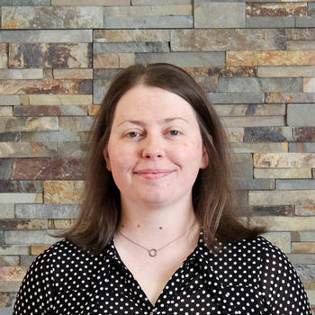 A smiling Megan Keener in front of a natural stone backdrop