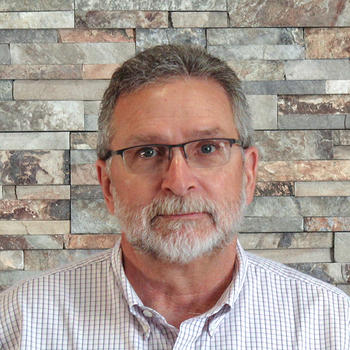 A dapper Mike Mahon in front of a natural stone backdrop