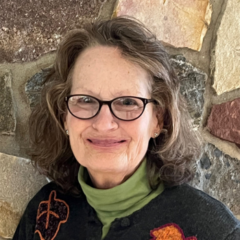 A smiling Joan Galbraith in front of a natural stone backdrop