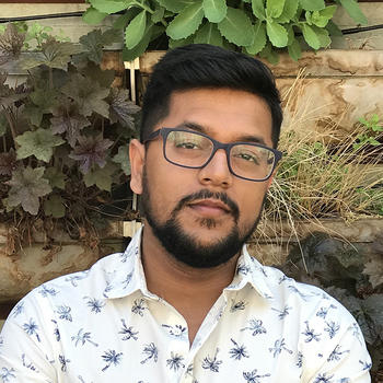 Shak Chowdhury standing near some greenery