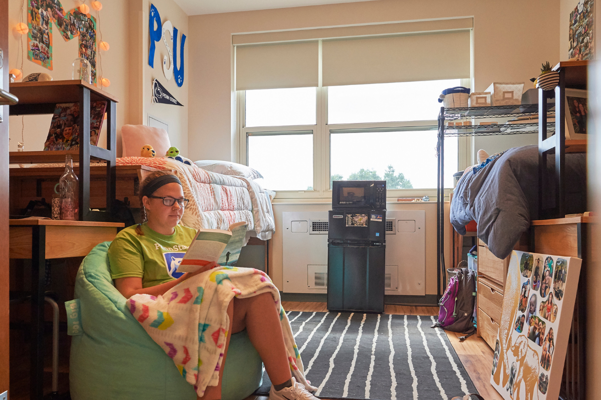 student sitting on a bean bag reading in her room