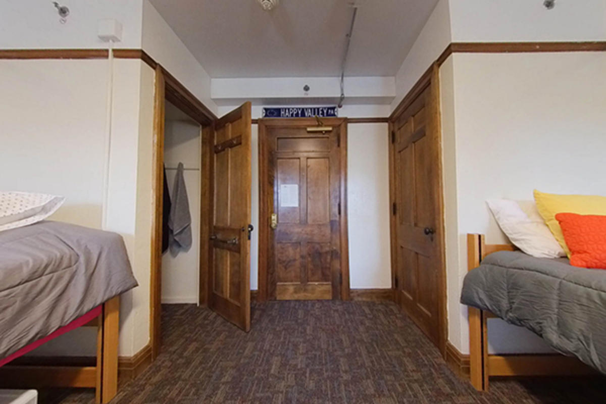 A tidy dorm room with two beds and hanging towels.