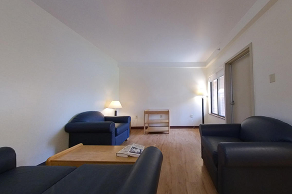 An empty living room with sofas, a table, and lamps.