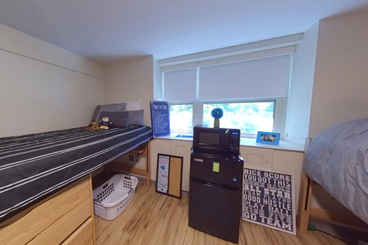 A neatly organized dorm room with two beds, appliances, and personal items.