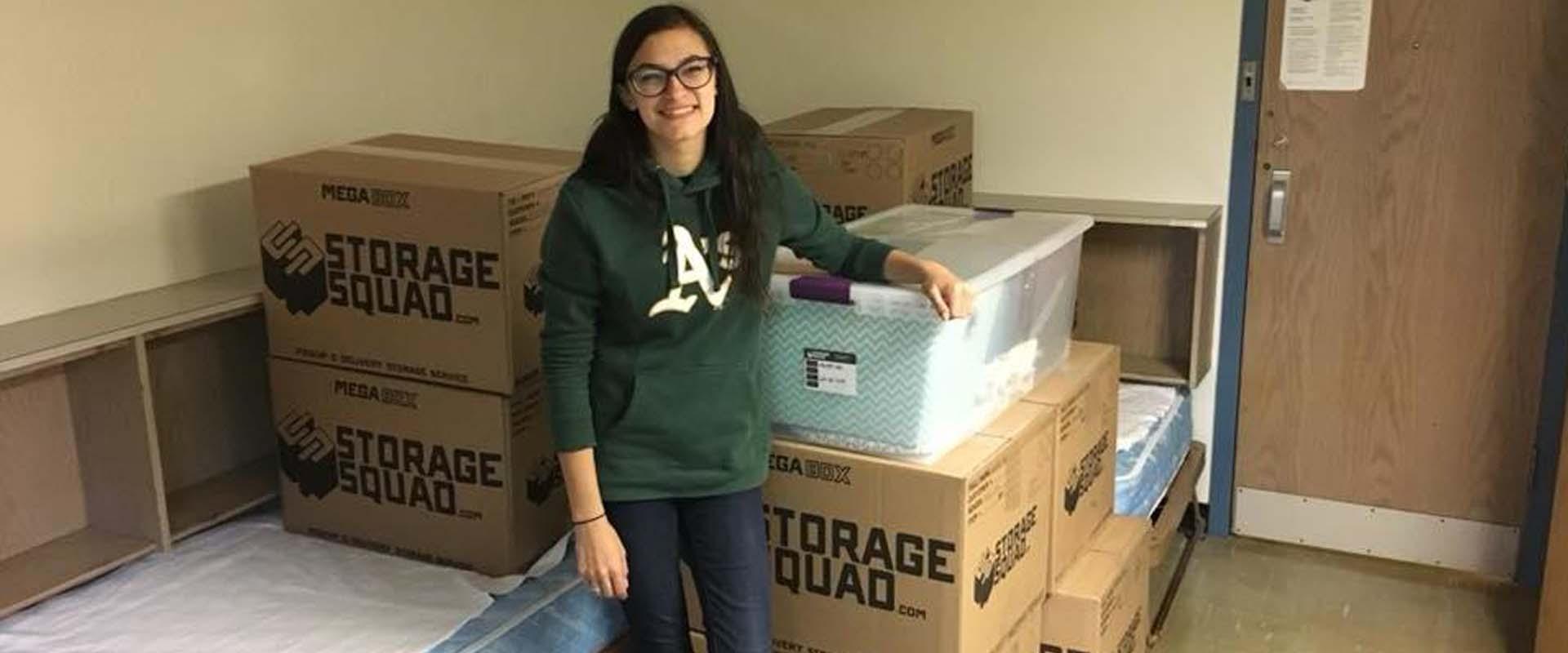 student standing next to her boxed belongings