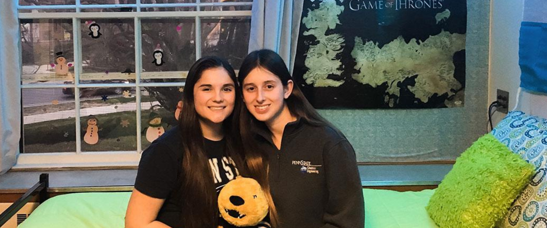 2 female students sitting on bed in residence hall room roommates