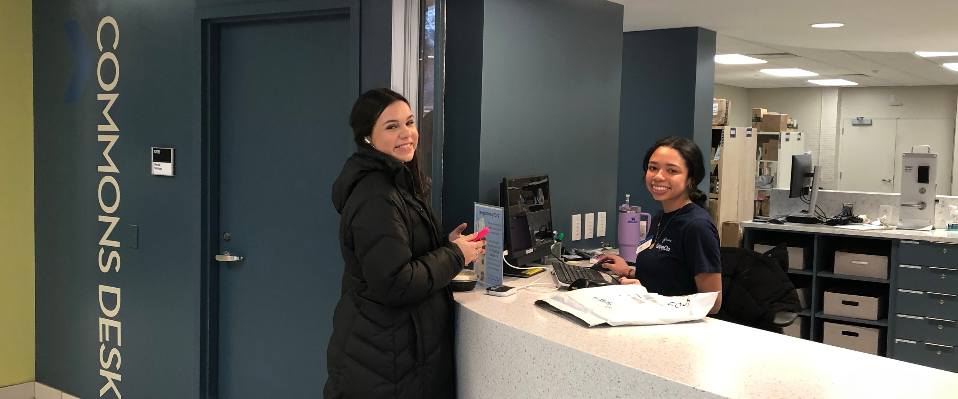 Commons Desk Operations student at commons desk counter being handed a package from staff