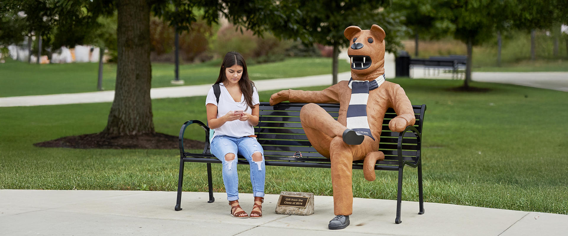 Penn State Altoona Student sits on bench next to Nittany Lion mascot